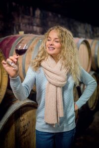 Jeune femme oeunologue inspecte la couleur et la robe d'un verre de vin rouge du bugey AOC dans le caveau Bonnard