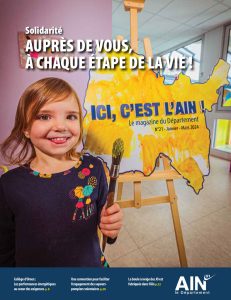 Couverture du magazine Ici c'est l'Ain : une petite fille qui souri un pinceau à la main en train de peindre une carte de l'Ain