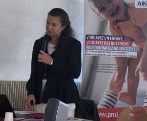 Docteur Anne-Lise Ducanda avec un micro devant une affiche de la PMI