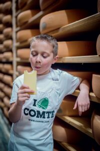 jeune garçon qui déguste un morceau de comté dans la fromagerie de la Combe du Val, du département de l'Ain